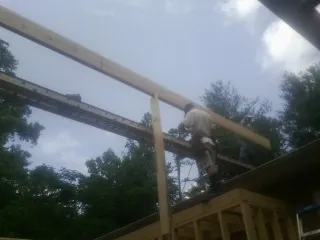 Carpenter setting a ridge beam over a new addition frame — Ice Dam Removal by Roofing Brothers in Honeoye Falls