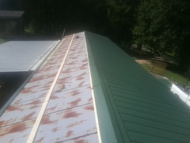 Old rusted panels beside newly installed green metal roofing — Wind Damage Roof Repair by Roofing Brothers in Honeoye Falls