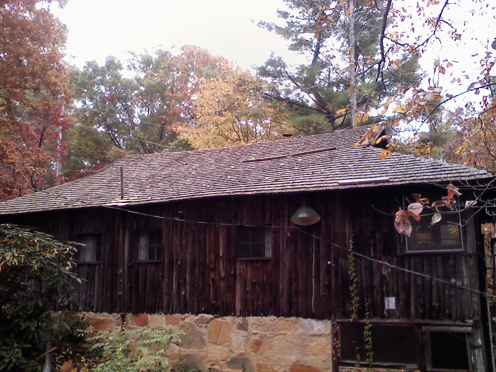 Weathered wood shake roof on a rustic board sided cabin in Honeoye Falls