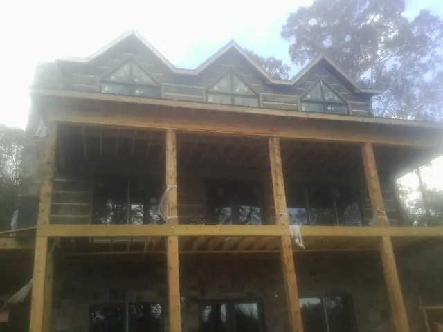 Dormers and porch framing on a large log home under construction — Roof Coating work by our crew in Honeoye Falls