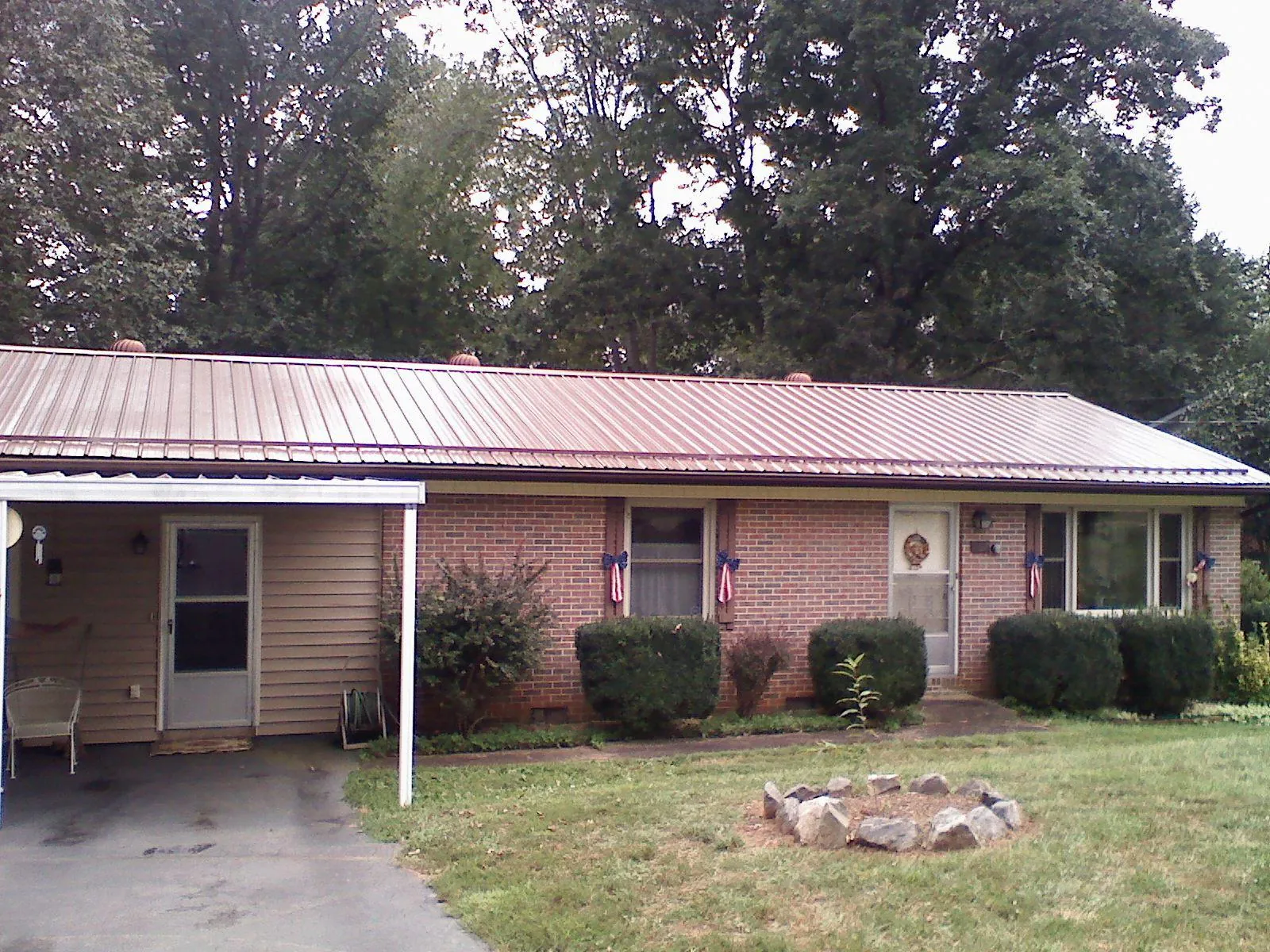 Bronze metal roof and carport on a brick ranch home — Roof Repair work by our crew in Honeoye Falls