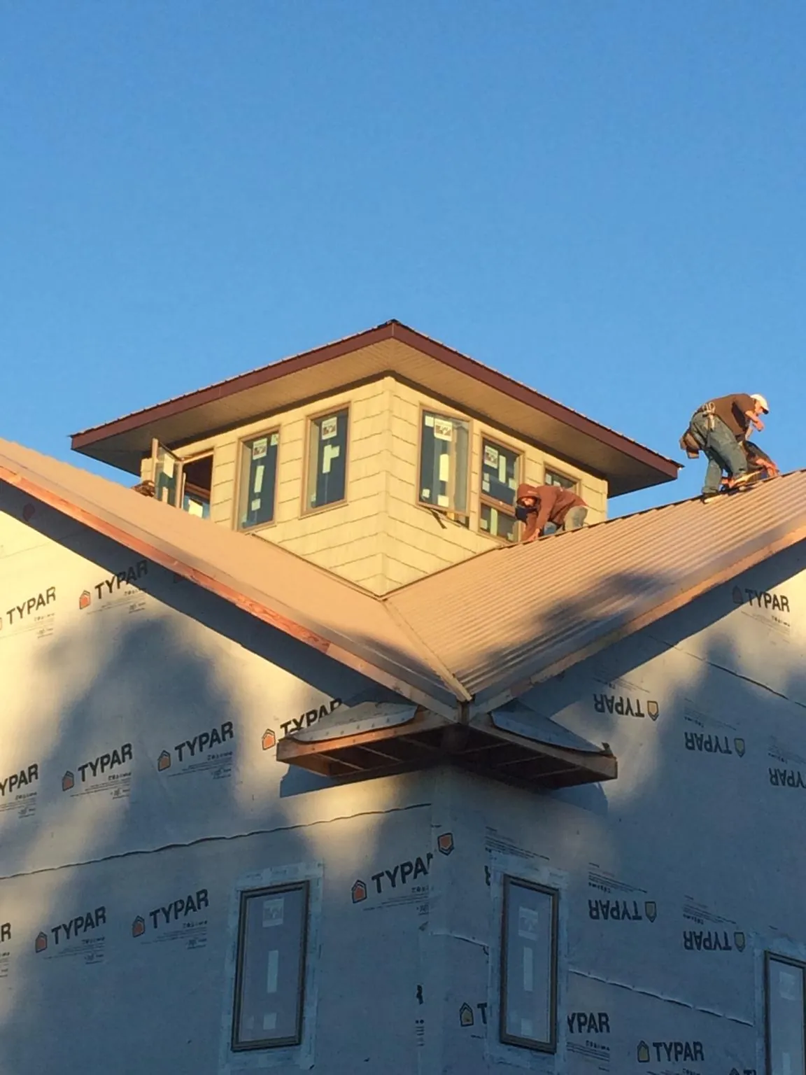 Roofers working around a rooftop cupola on a new metal roof at sunset — Roof Waterproofing in Honeoye Falls by Roofing Brothers
